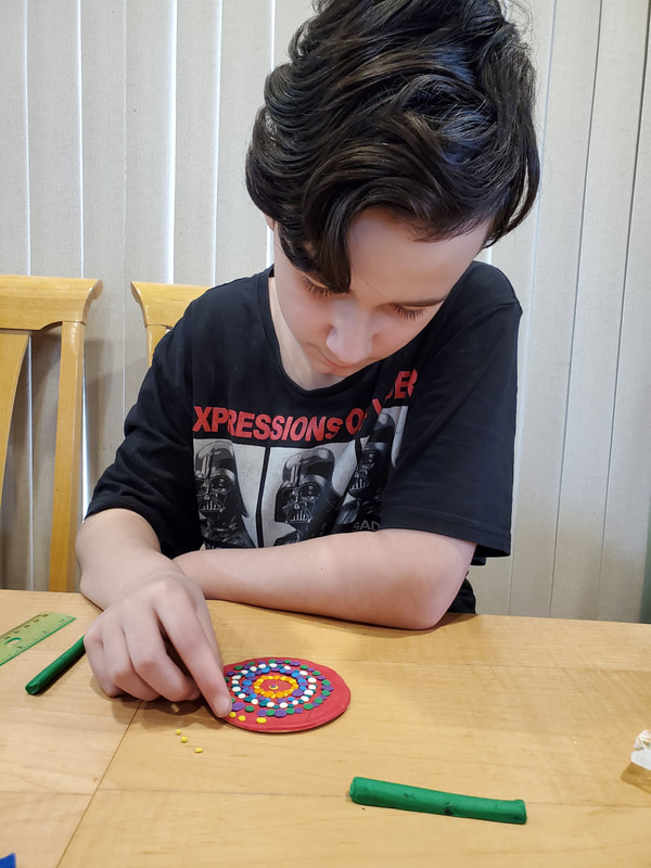 Boy sitting at table creating art with plasticine.
